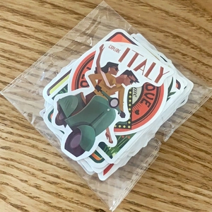 Detail of travel theme stickers in clear bag showing vintage Italy scooter illustration
