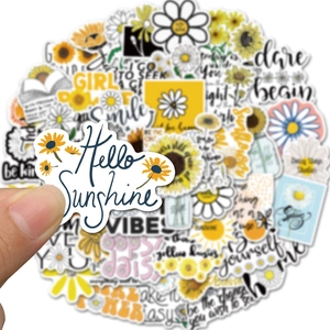 Close-up of a waterproof daisy sticker being held, showing vibrant yellow floral design details