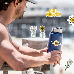 Waterproof sunflower and daisy stickers set on a blue sports bottle in an outdoor setting