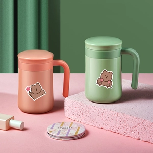 Close-up of pink and green insulated mugs decorated with cute brown bear stickers