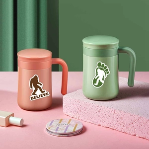Close-up of pink and green mugs featuring Bigfoot stickers and Believe typography