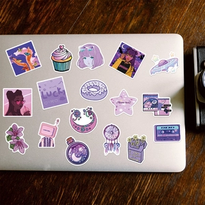 Macro shot of 50 purple Y2K aesthetic waterproof PVC stickers on a silver laptop surface