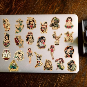 Close-up of vintage sailor tattoo stickers applied on a silver laptop on a wooden desk