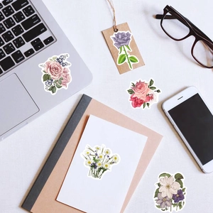 Flat lay of floral stickers on laptop and notebook with elegant rose and flower designs