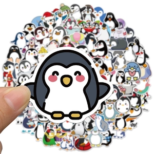 Gros plan d'une main tenant un autocollant pingouin mignon d'un ensemble de 100 pièces