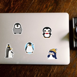 Gros plan d'autocollants pingouins mignons sur un ordinateur portable en argent