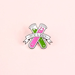Creative enamel test tube brooch with colorful liquids and banner on pink background