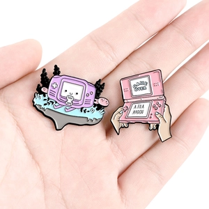Detailed view of hand holding retro purple and pink game console enamel lapel pins