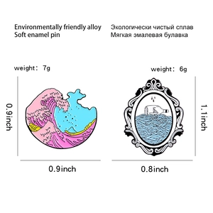 Detailed view of alloy enamel pins showing pink sea waves and a sailboat in a glass bottle