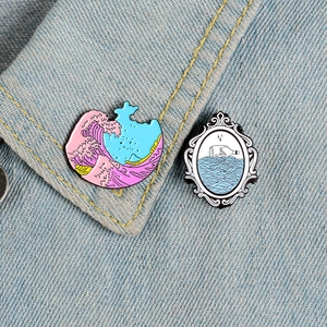 Retro mirror and wave enamel pin set with pink sea spray on denim jacket collar