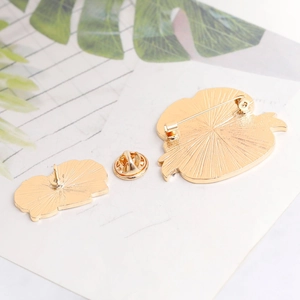 Detailed back view of gold metal brooch set showing sunray texture and safety pin clasp