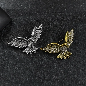 Vue détaillée de broches aigle avec texture de plumes et cristaux sur support noir chic