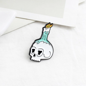 Gothic skull enamel pin with melting green candle and yellow flame on white background