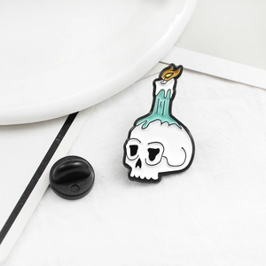 Detail of creative skull and melting candle enamel brooch with bright flame colors