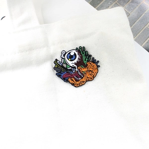 Halloween enamel pin with eyeball monster on skateboard pinned to a canvas bag