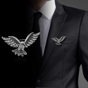 Détail de la broche aigle avec strass blancs sur costume noir et son reflet