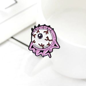 Close-up of a pink alien eyeball enamel pin with red veins on a white ceramic cup edge