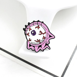 Alien eyeball enamel pin with bloodshot veins and pink body on a display stand