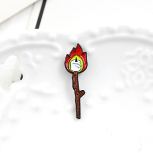 Creative enamel brooch featuring a roasted marshmallow over a flame on a wooden stick