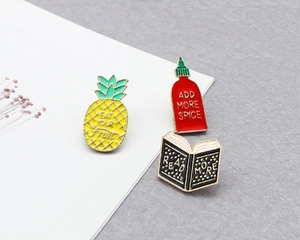 Detailed close-up of fruit, spicy sauce, and book enamel pins set on a textured background