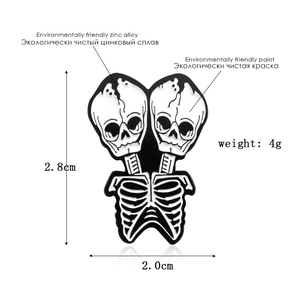 Macro detail of conjoined skull enamel pin showing 2.8cm x 2.0cm product dimensions