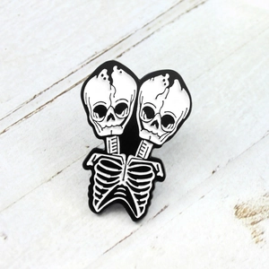 Gothic punk style dual head skeleton enamel pin with black and white bones detail