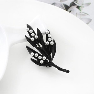Détail de la broche en forme de feuille d'érable noire mate sertie de petites perles