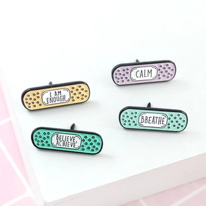 Set of four pastel bandage-shaped enamel pins featuring inspirational English slogans