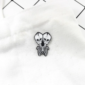 Gothic punk conjoined twin skull enamel pin badge on white canvas fabric background