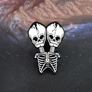 Gothic punk conjoined twin skull enamel pin with intricate ribcage detail on starry background