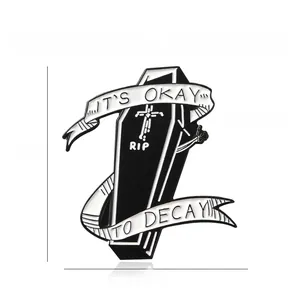 Detail of gothic coffin enamel pin with ribbon and text It's okay to decay