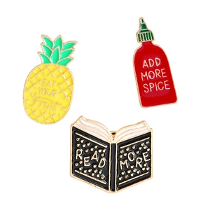 Three-piece enamel pin set with pineapple, hot sauce bottle, and book designs