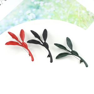 Three minimalist leaf-shaped brooches in matte red, black and dark green metal finish
