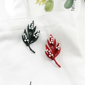 Détail de broches en forme de feuille rétro avec perles sur un sac en toile blanc