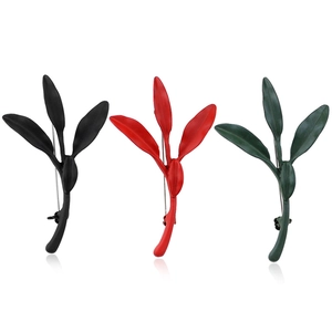 Three minimalist tea leaf brooches in matte black red and green finish on white background