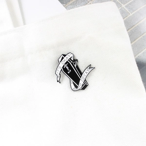 Gothic coffin enamel pin detail with RIP text and white ribbon on canvas surface