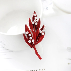 Élégante broche feuille d'érable rouge avec perles blanches sur une tasse blanche