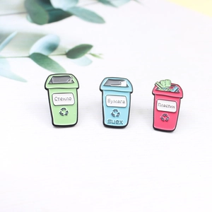 Detailed close-up of colorful enamel recycling bin pins with Russian text on wood surface