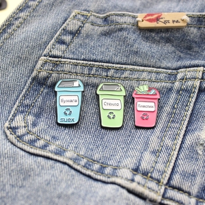 Three enamel trash can pins for recycling on blue denim pocket, eco-friendly brooch set