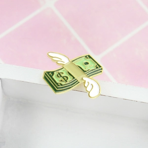 Detailed close-up of a winged dollar bill enamel pin featuring green and gold accents