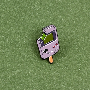 Creative purple game console popsicle enamel pin with bite mark on green felt