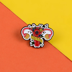 Detail of enamel uterus brooch with red flowers and yellow Grow A Pair ribbon