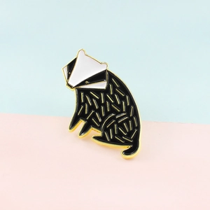 Détail d'un pin's blaireau en émail avec placage à l'or et motif noir et blanc gouttelette