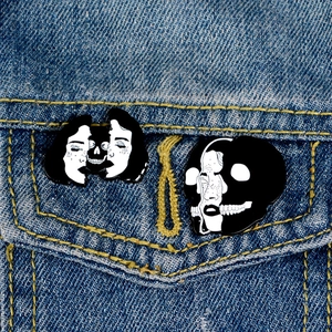 Artistic split-face witch skull enamel pins on denim jacket with surreal black and white design
