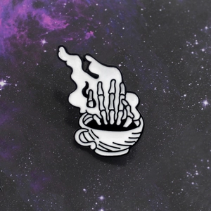 Gothic punk enamel pin featuring a skeleton hand emerging from a coffee cup in white