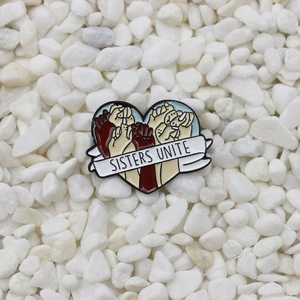 Broche en émail Sisters Unite avec mains diverses sur fond de galets blancs naturels