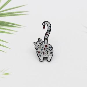 Broche chat en émail blanc pailleté entouré de guirlandes festives et longue queue