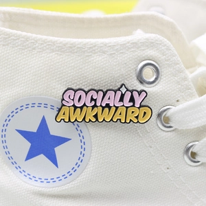 Socially Awkward enamel pin badge featuring 3D colorful letters on a canvas sneaker