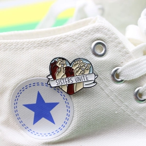Broche cœur émaillée Sisters Unite avec poings unis sur fond de basket en toile blanche