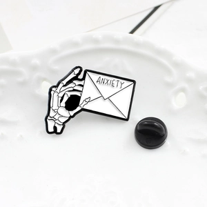 Macro shot of punk skull hand holding ANXIETY envelope pin with rubber backing